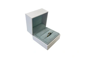 An elegant white rigid jewelry box featuring a soft slate-blue velvet interior with a single ring slot. Manufactured by FSC-certified ZY Pack, utilizing 15 years of expert structural design to provide sustainable and luxury packaging for global jewelry retailers