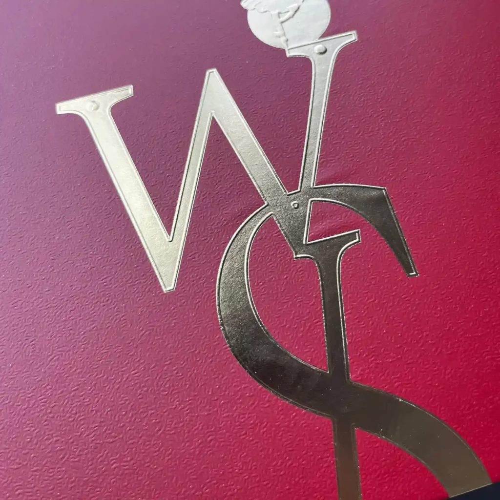 Intricate 3D embossed gold foil logo featuring a rabbit character and monogram, demonstrating high-pressure adhesion on textured specialty paper.