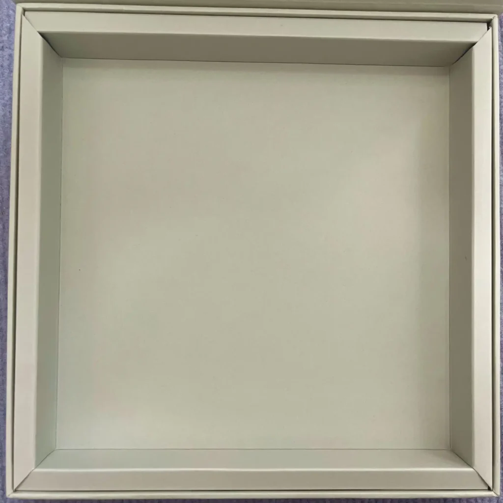 Beige cardstock insert tray for lightweight cosmetic sets. Simple die-cut folding structure.