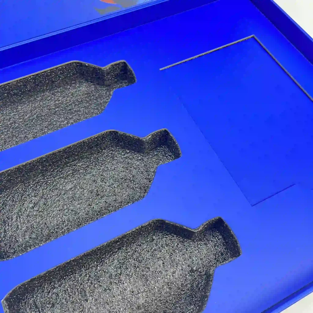 Hybrid packaging insert featuring a printed rigid cardboard top laminated onto a white low-density EPE foam base. Ideal for branding display in gift sets.