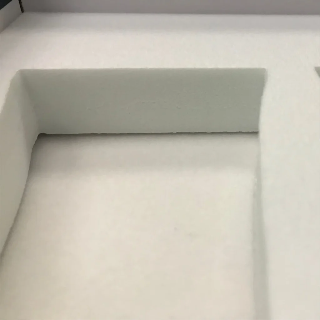 White low-density EVA foam insert with custom die-cut compartments. Features a high-expansion structure (Shore 15-25°) that offers a soft-touch surface and cushioning for electronics, distinct from rigid high-density EVA.