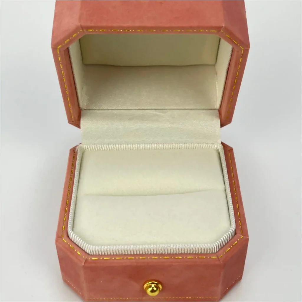 Interior of a reddish-orange octagonal ring box (Coral tone). Features a high-density sponge core fully wrapped in premium suede microfiber, forming a tight slot to securely hold diamond rings.