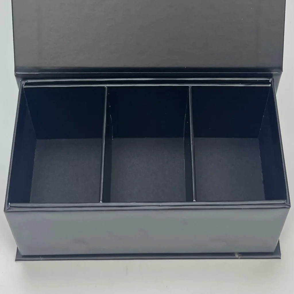 Black rigid box with interlocking chipboard dividers. Creates sturdy compartments for gift sets, non-foldable structure.