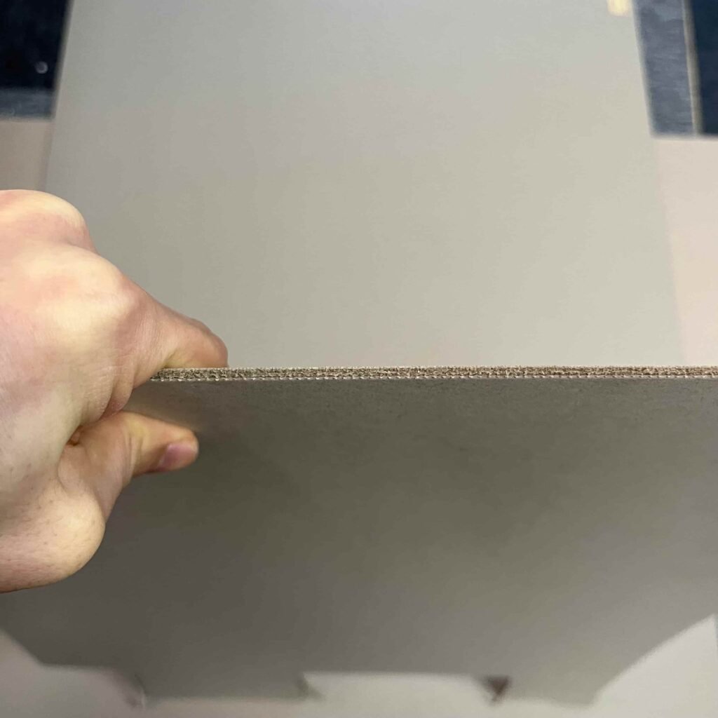 Demonstration of paperboard bending easily when the grain direction is incorrectly aligned, leading to sagging lids.