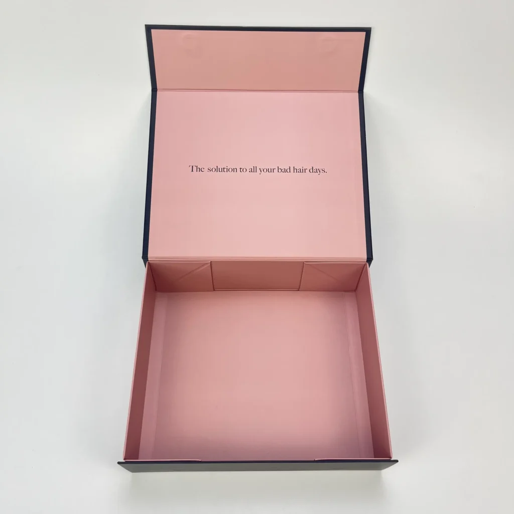 Pink magnetic folding box with adhesive tape open position showing branded interior lid print and corner gusset structure