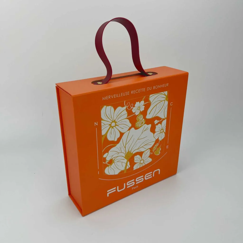 Orange magnetic foldable rigid box with burgundy PU handle featuring custom floral print design for luxury brand gift packaging