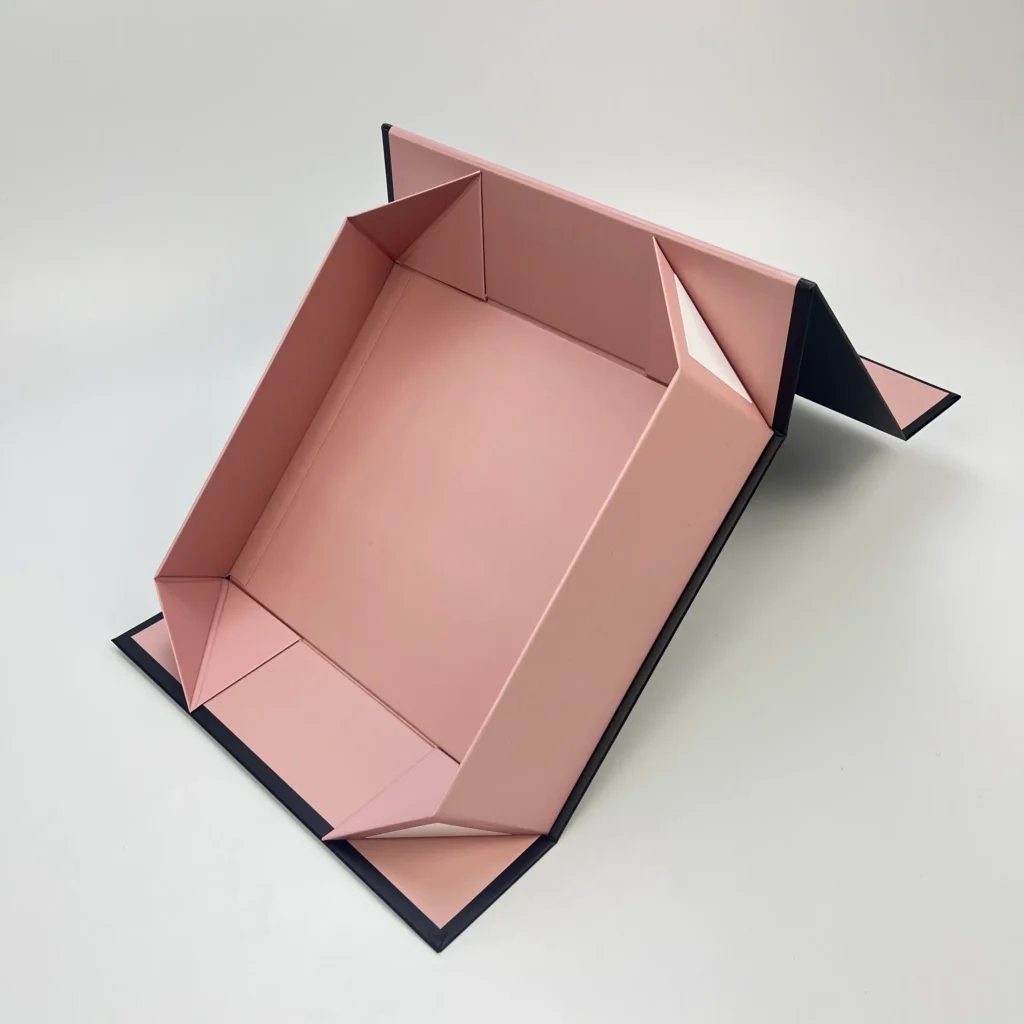 Pink magnetic folding box with adhesive tape open flat showing collapsible rigid structure and black edge trim